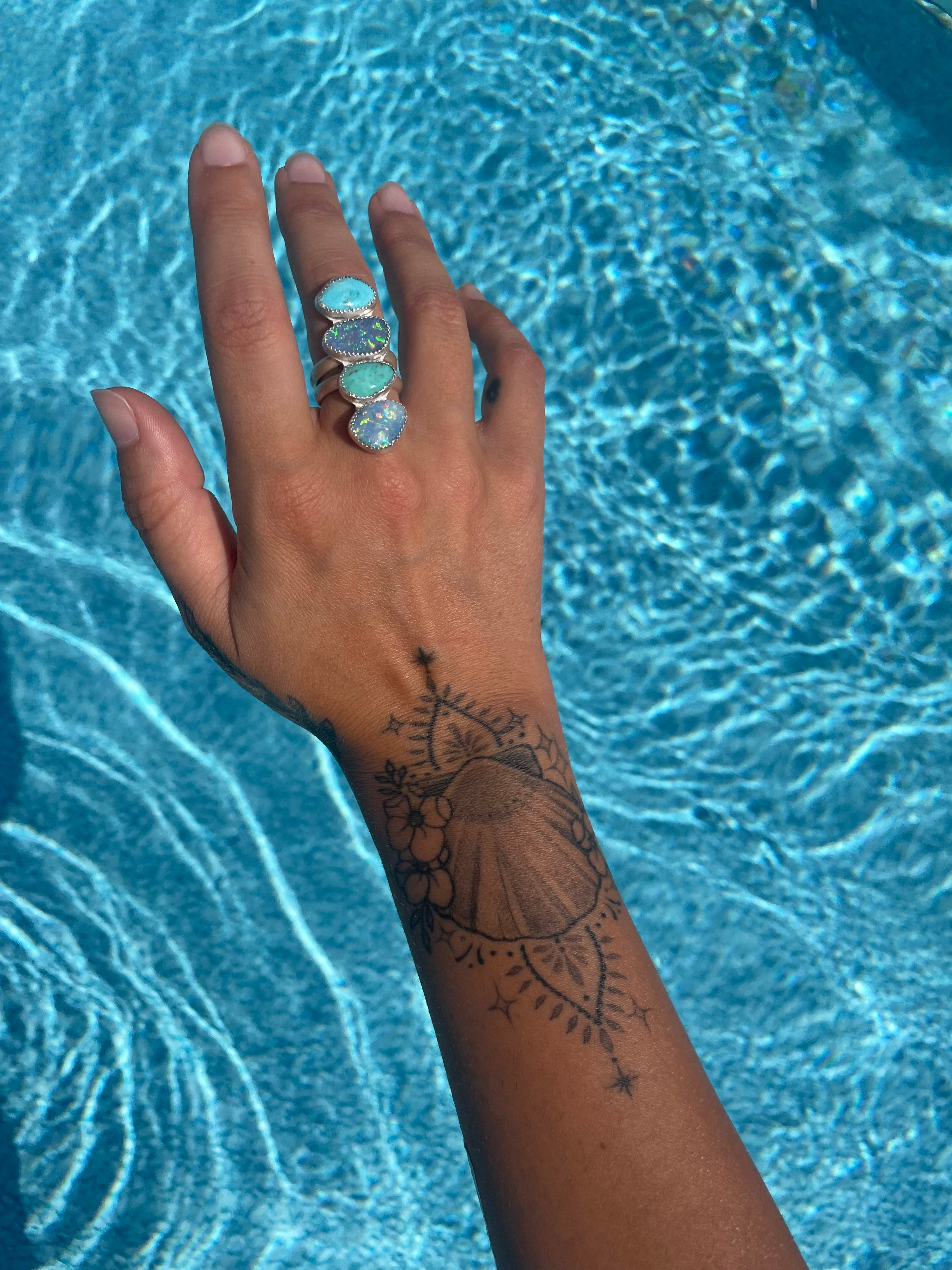 Unique turquoise jewelry on a tattooed hand 